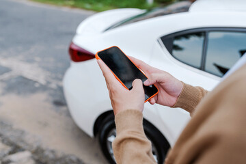 Man holding mobile phone next to door of his car in the street