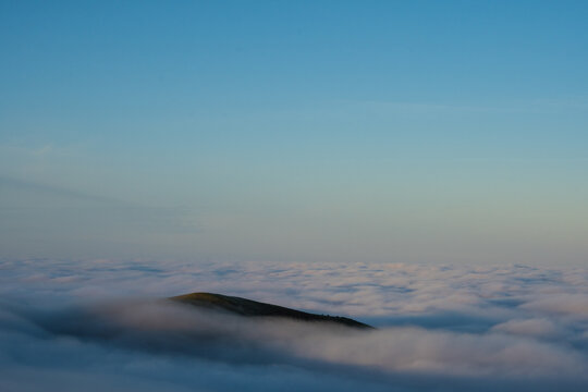 A Hill Poking Above The Clouds