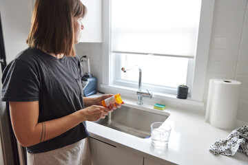 Woman taking pills in the kitchen
