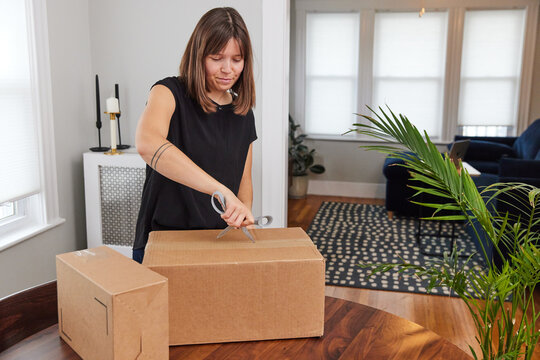 Woman opening a shipment received by mail with scissors