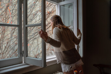 Woman opening the window in the morning