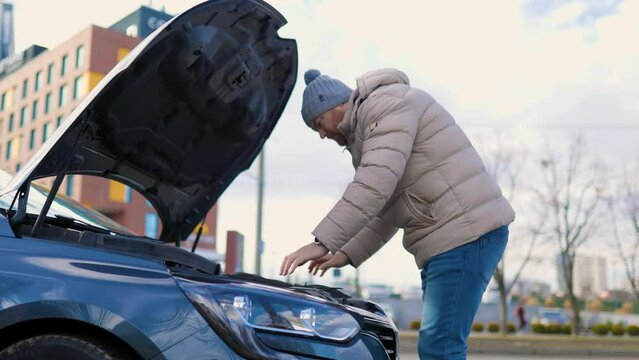 A man open the hood is seen working on a broken car,