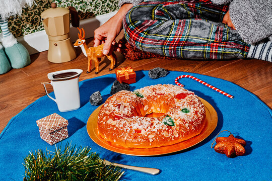 man in pajamas sitting on the floor next to a spanish king cake