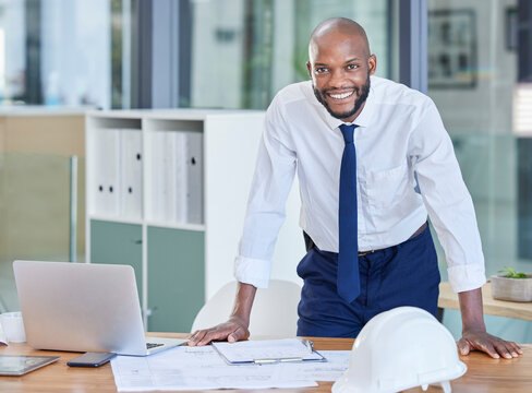 Portrait, black man and architect in office, laptop and achievement with startup, manager or smile. Nigerian male employee, confident leader or engineer with blueprints, happiness or business success