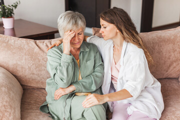 Grown up daughter soothe aged mother holds her hand feel empathy give her moral support, sad...
