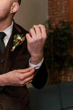 groom touching cufflinks on his suit