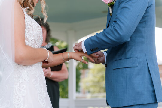 man in blue suit putting wedding ring on his wife's finger at wedding