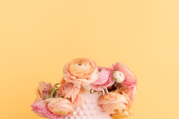 Wilted ranunculus flowers in a pink vase