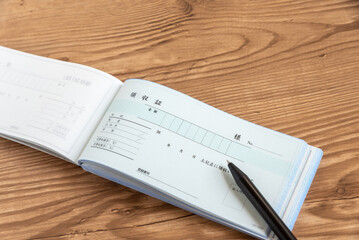 領収証とボールペン　木目背景