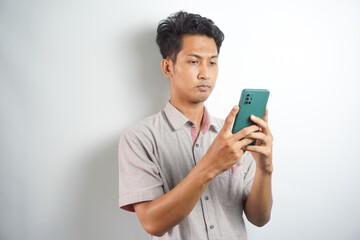 Asian man seriously concentrated on smartphone isolated on white background