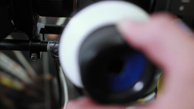 Cameraman operator turns follow focus on digital cinema camera during filming movie indoors. Backstage. Cinematography. Production of commercial ad or TV series. DOP on set. Stage, scene. Videography
