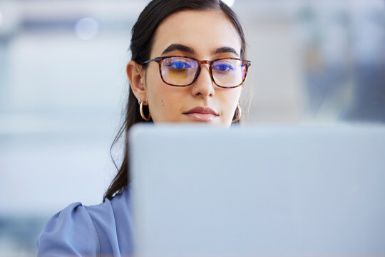 Business woman, glasses and working on laptop in office, agency and startup company. Focus, face and female worker on computer technology for email, internet planning and professional seo research