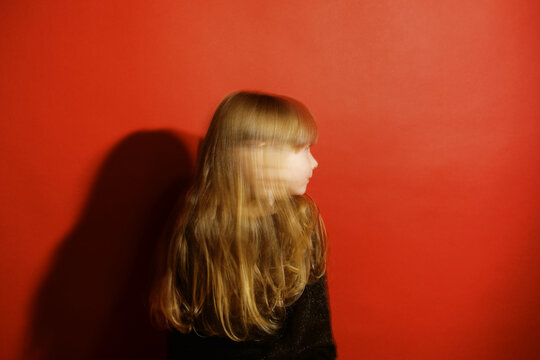 Blurry Portrait Of Girl In Front Of Red Wall