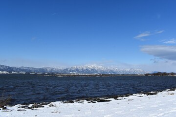 雪が積もった琵琶湖畔と比良山