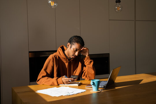 Man paying utility bills from home calculating expenses