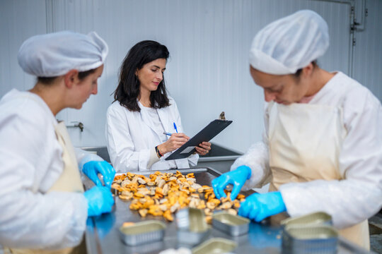 Inspector with clipboard watching canning of seafood