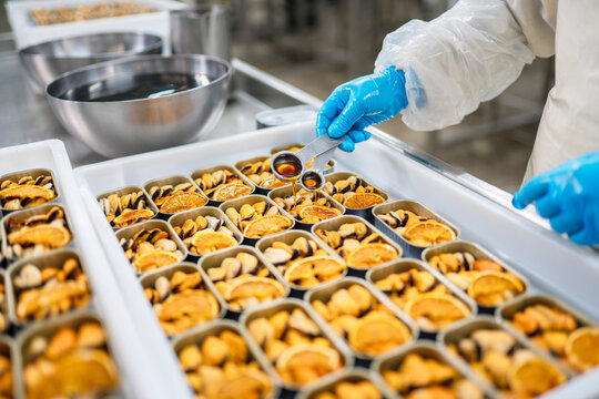 Crop employee adding oil to canned mussels