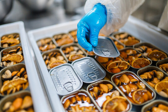 Crop worker putting lids on cans