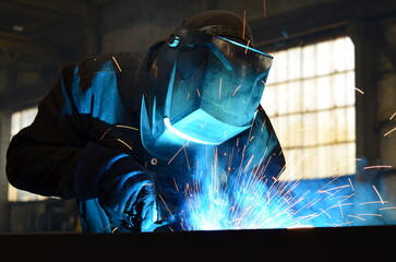 Workers wearing industrial uniforms and Welded Iron Mask at Steel welding plants, industrial safety first	