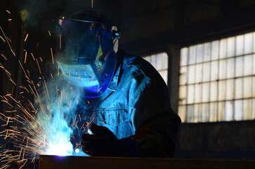 Workers wearing industrial uniforms and Welded Iron Mask at Steel welding plants, industrial safety first	