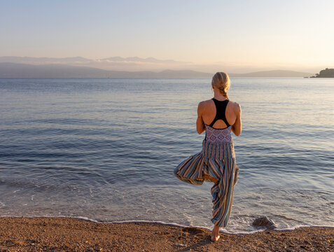 Woman in yoga tree pose on the beach