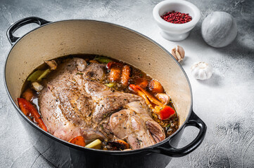 Braised lamb mutton shoulder in a baking dish with vegetables in red wine. White background. Top...