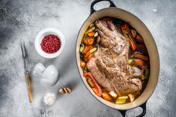 Braised lamb mutton shoulder in a baking dish with vegetables in red wine. White background. Top view
