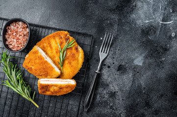 Schnitzel Cordon bleu fillet cutlet with ham and cheese. Black background. Top view. Copy space - obrazy, fototapety, plakaty