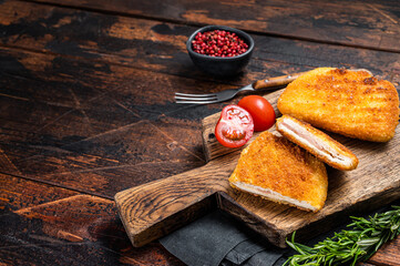 Crispy Cordon Blue Chicken fillet roll with ham and cheese served  on a wooden board. Wooden...