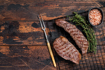 Grilled Sirloin flap or Bavette beef meat steak on a griil with herbs. Wooden background. Top view....