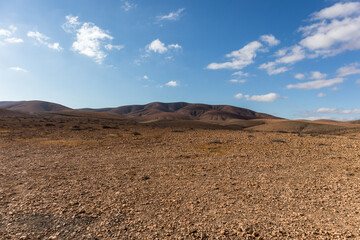 amazing desert landscape with blue sky and white clouds with mountain range in the background. Fuerteventura, Canary Islands, Spain
