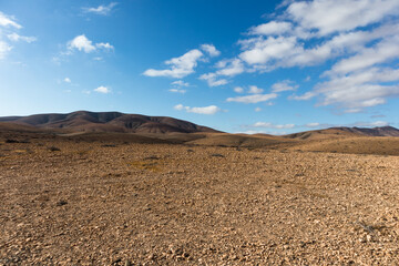 amazing desert landscape with blue sky and white clouds with mountain range in the background. Fuerteventura, Canary Islands, Spain