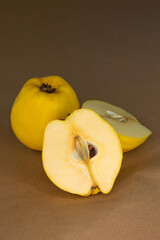 Whole and sectioned yellow quince fruits on brown baking paper background
