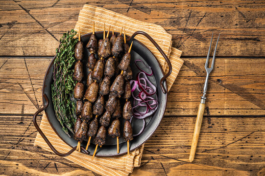 Churrasco Brazilian barbecue, chicken hearts grilled kebabs with herbs and vegetables. Wooden background. Top view