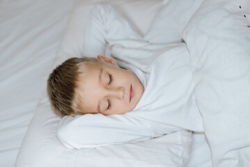 Fototapeta na wymiar Мальчик спит в кровати . белая постель