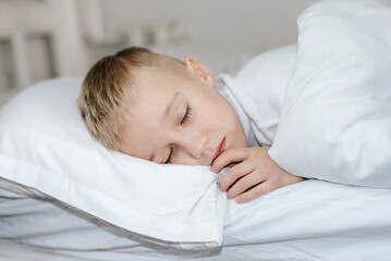 Obraz na płótnie Canvas Мальчик спит в кровати . белая постель