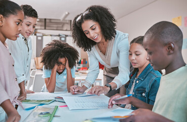Female teacher helping children with assignment, classroom in school and writing notes in book. Diversity in student group, educator reading kids notebook and learning together for assessment