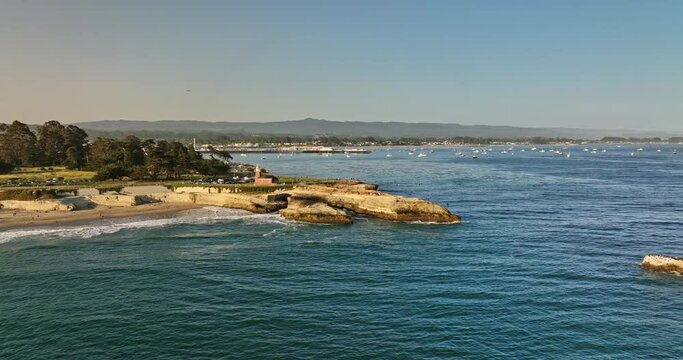 Santa Cruz California Aerial v1 fly around lighthouse point and seal rock with waves crashing on the shore, panning view reveals glowing sun in the sky at sunset - Shot with Mavic 3 Cine - May 2022