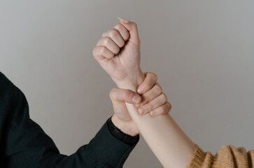 Domestic violence. Man's hand grabbing a woman's arm. Concept of gender violence and mistreatment of women. Background isolated on gray background. - obrazy, fototapety, plakaty