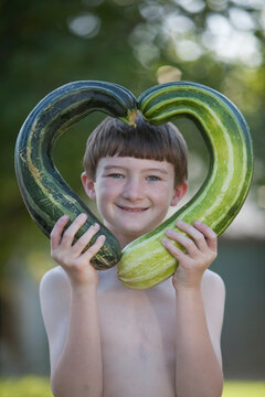 Boy, age 9, holding zucchini in shape of a heart
