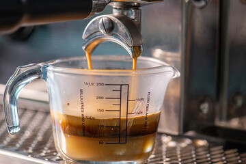 cup of hot Intense coffee dark shot in glass on wooden table with beans with crema. coffee beans and cup full of Intense dark shot coffee in glass cup