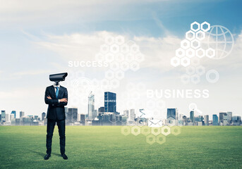 Camera headed man standing on green grass against modern cityscape