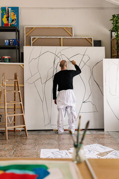 an artist sketching a large-format canvas with charcoal