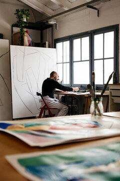 a painter in his studio, making sketches.