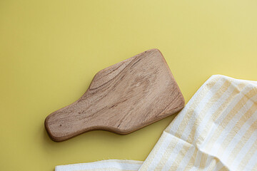 Small wooden cutting board placed on a yellow background