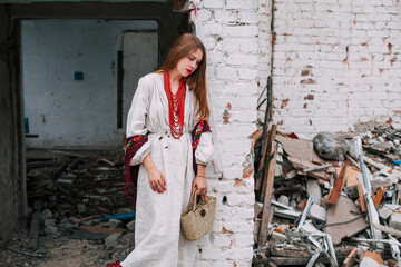 Art work on the theme of the war in Ukraine. A frustrated Ukrainian woman in national clothes and a bag in her hands stands near the ruins of a building bombed by the Russian army.