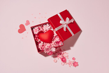 Open gift box with a cute little heart inside on pink background