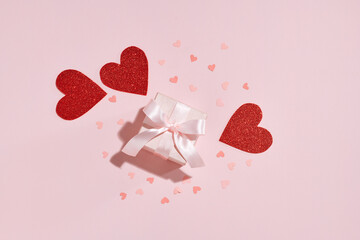 Gift box with red hearts on pink background
