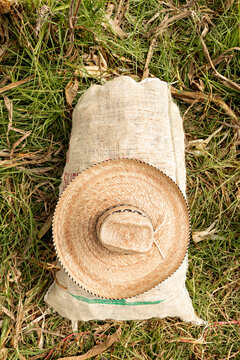Straw hat on a sack full of corn thrown on the grass