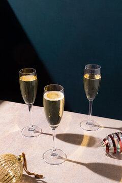three glasses of champagne next to christmas balls